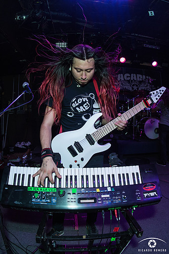A heavy metal musician from the band Immortal Guardian plays guitar and keyboards at the same time.