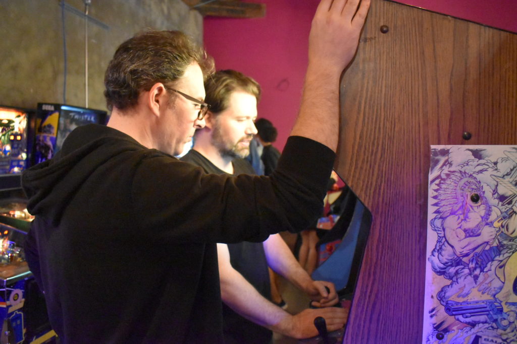 Retro gaming is king at Player One Arcade bar. Owner, Chris, looks on as a player goes for the high score.