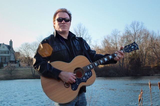 Guitarist Charles Parker poses in front of a lake for a promotion.