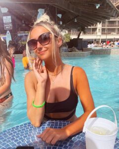 A young blonde girl sits at the bar in swimming pool