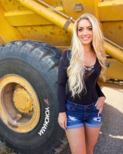 Sexy blonde Playmate, Holly Jo Anne White, poses in front of a piece of heavy construction equipment