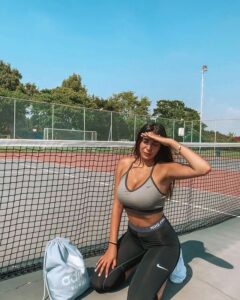Shani Shetach kneels on a tennis court